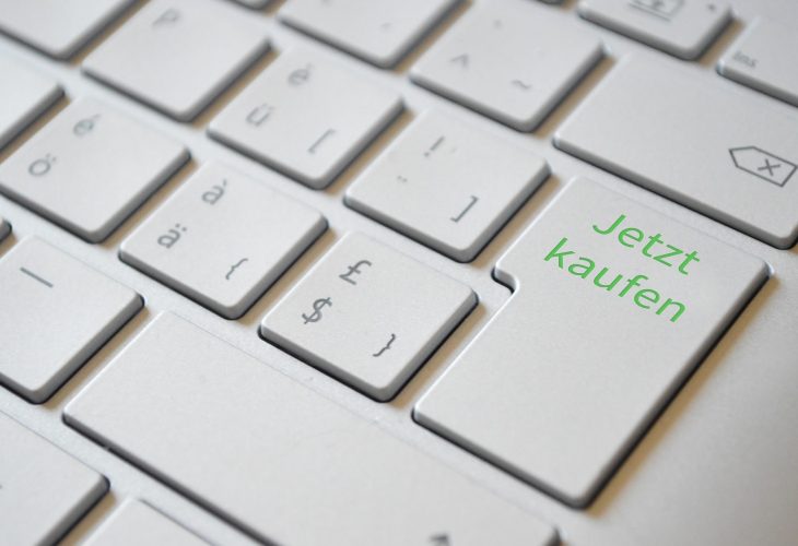 Nahaufnahme einer Computertastatur mit einer großen Eingabetaste, die in grüner Schrift den Text 'Jetzt kaufen' zeigt.