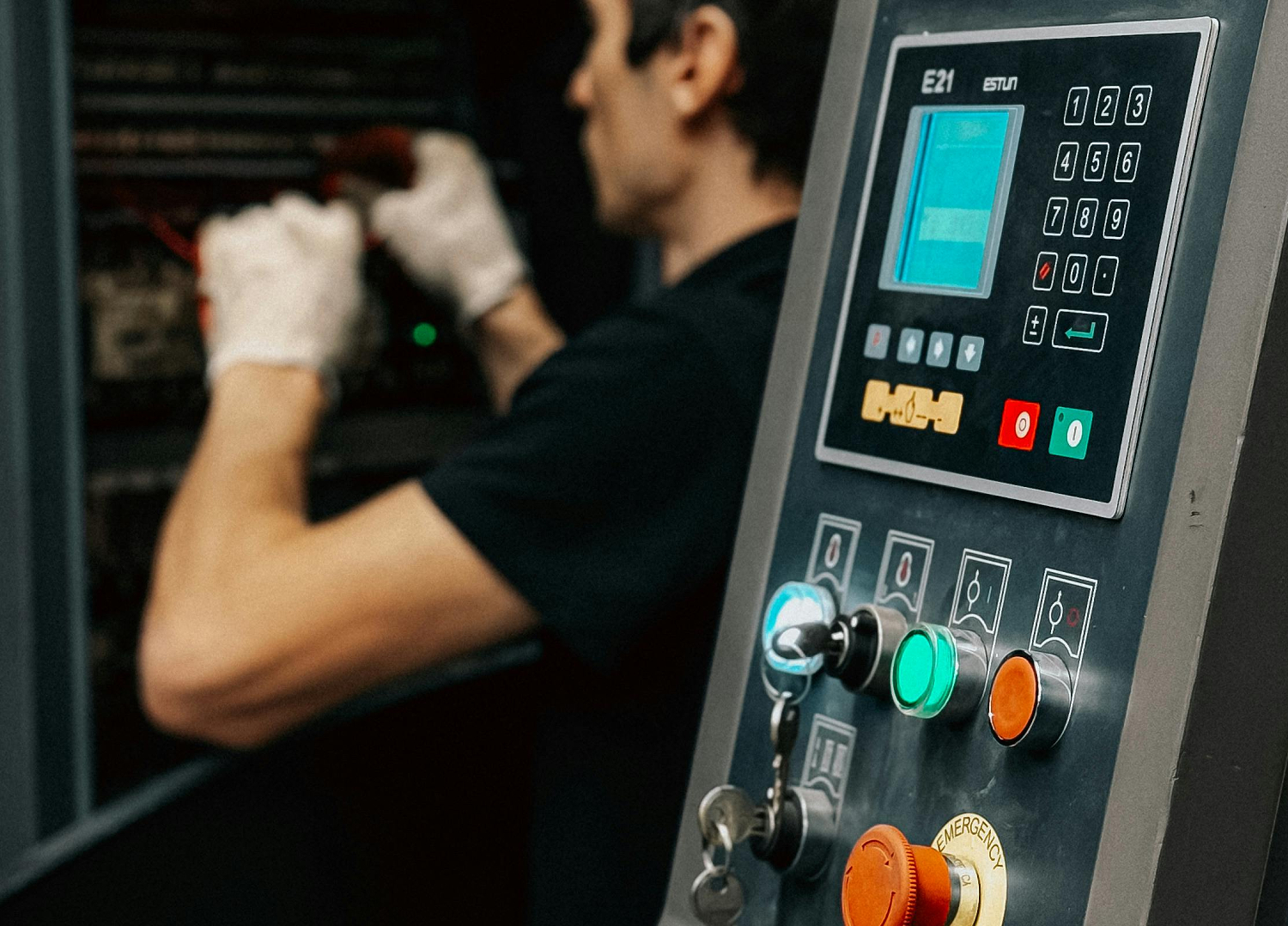 Ein Monteur arbeitet im Hintergrund an einer Maschine. Im Vordergrund befindet sich ein Bedien-Terminal.